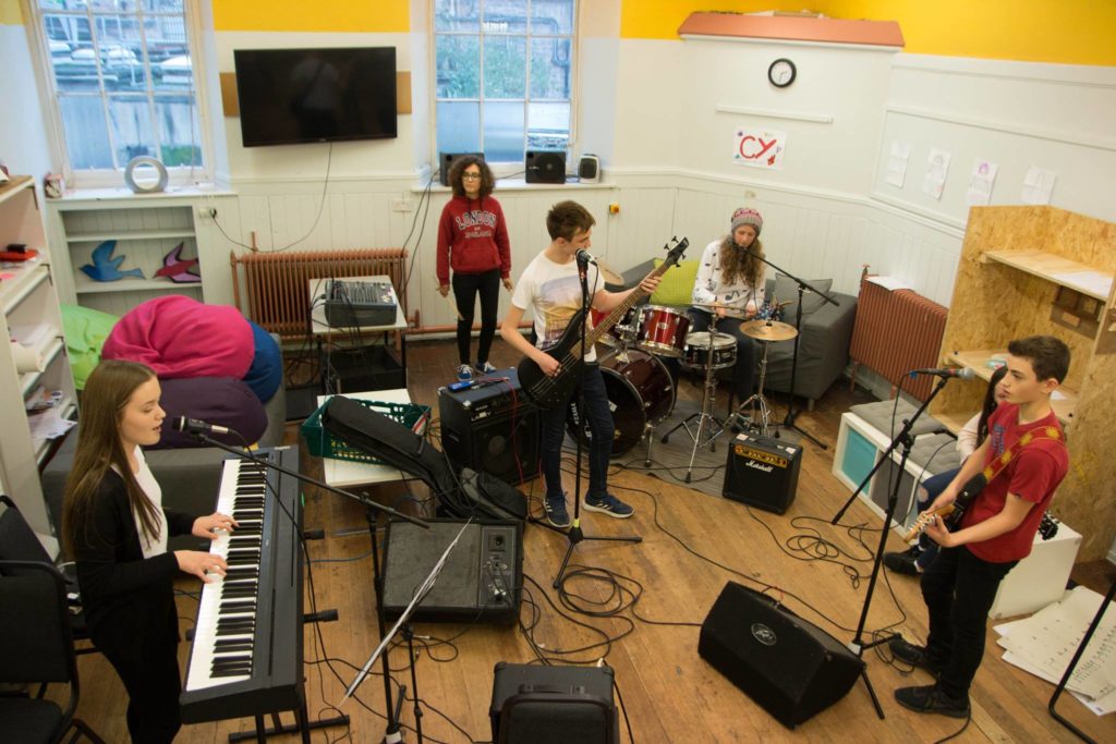 young people practising in a rehearsal room complete with equipment