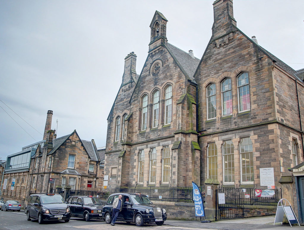 Exterior view of old stone Building in the middle of a busy Edinburgh City Centre